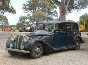 The Daimler outside with farm machinery in the background.